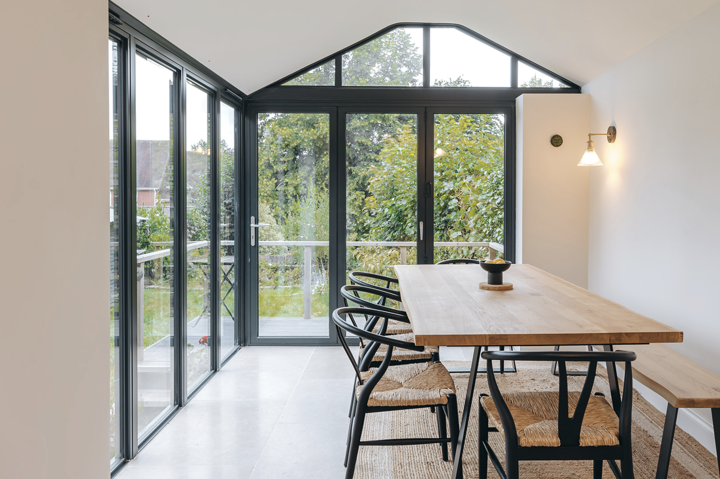 Completed glazed gable dining extension with black-framed glazing opening to a garden