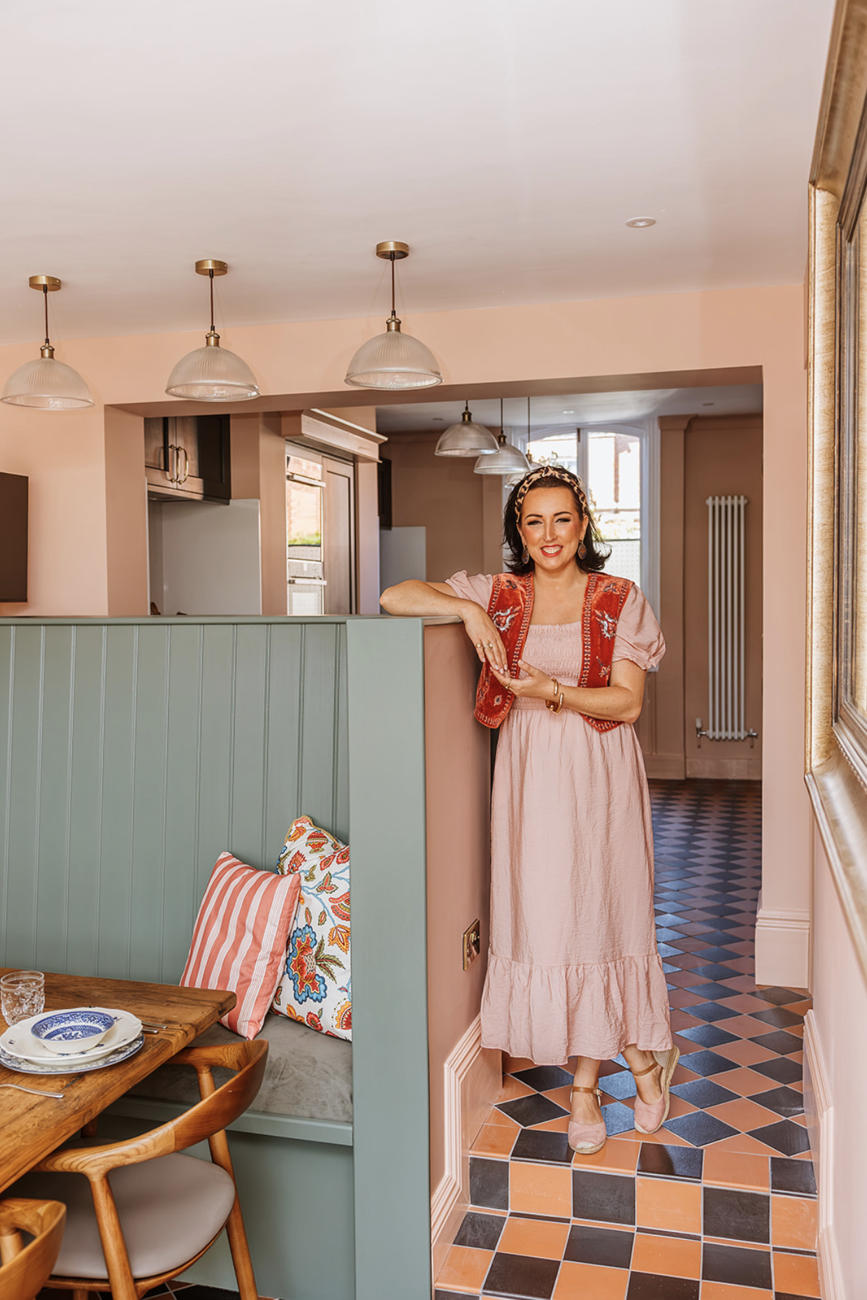 Camilla Monk standing in a completed whole-home remodel, with the reconfigured kitchen and dining space behind her
