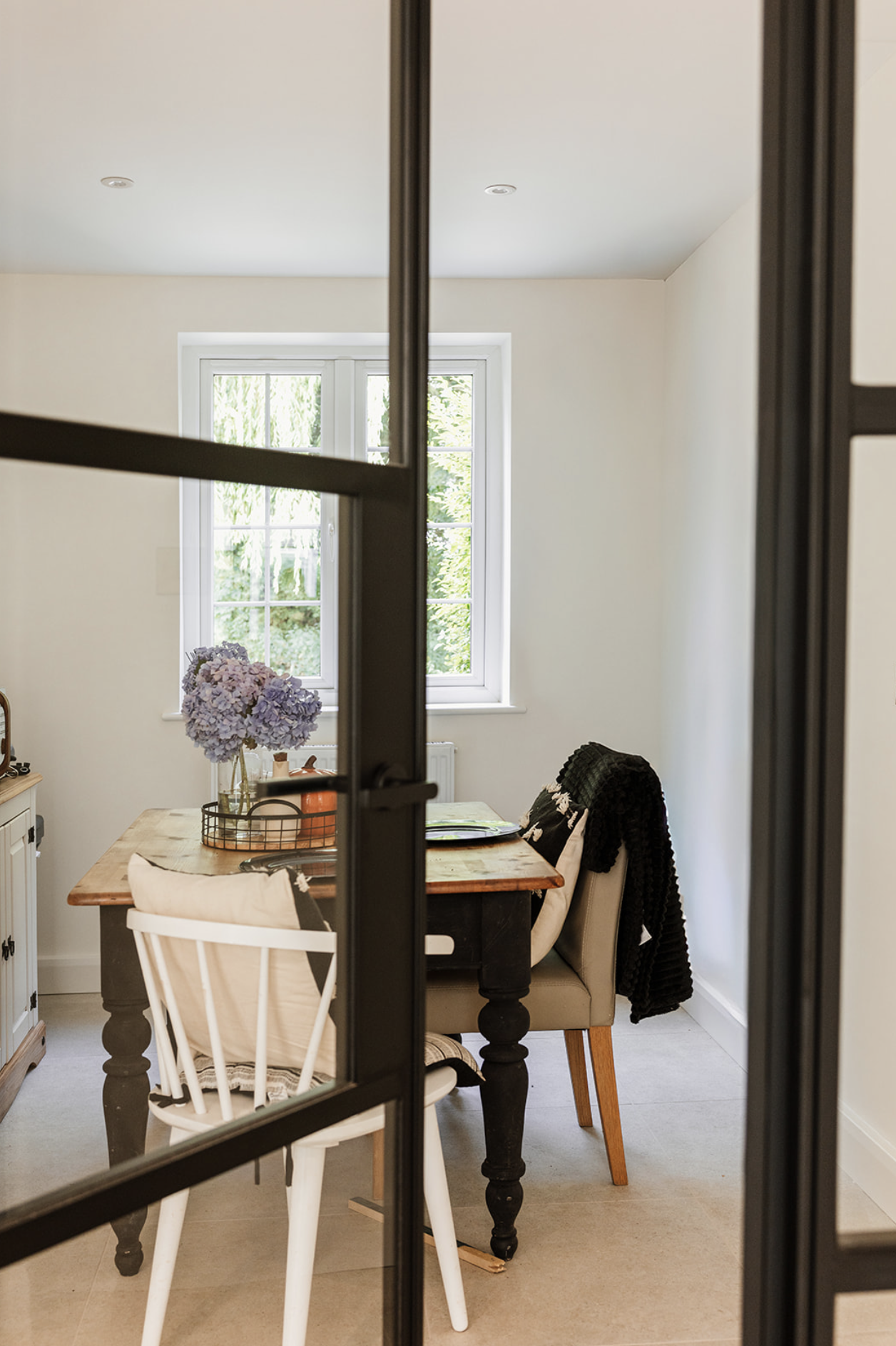 View across a dark green kitchen island through a wide opening to the sitting room beyond