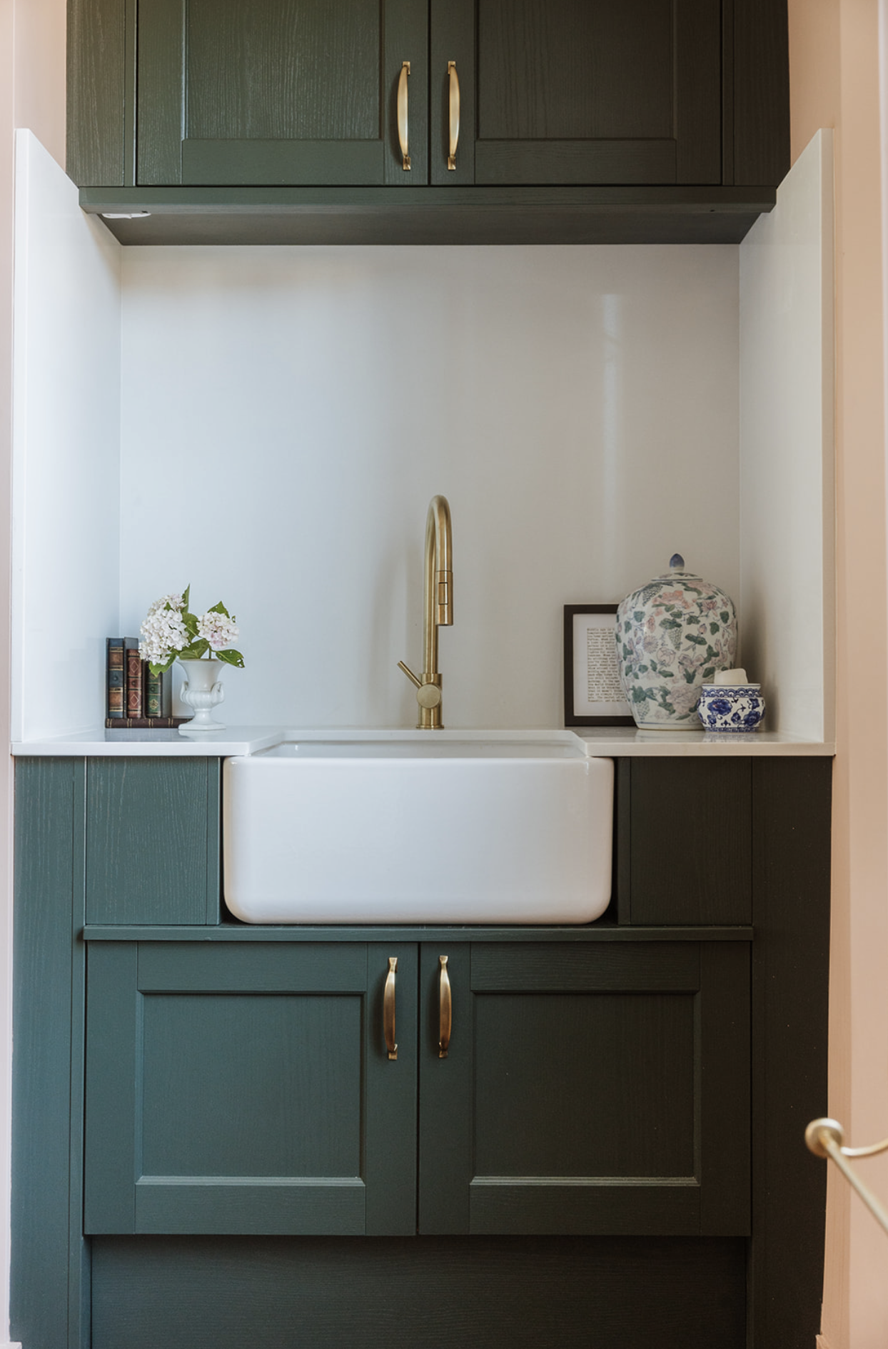 Deep green utility with butler sink, brass tap and shelf styling in a compact nook