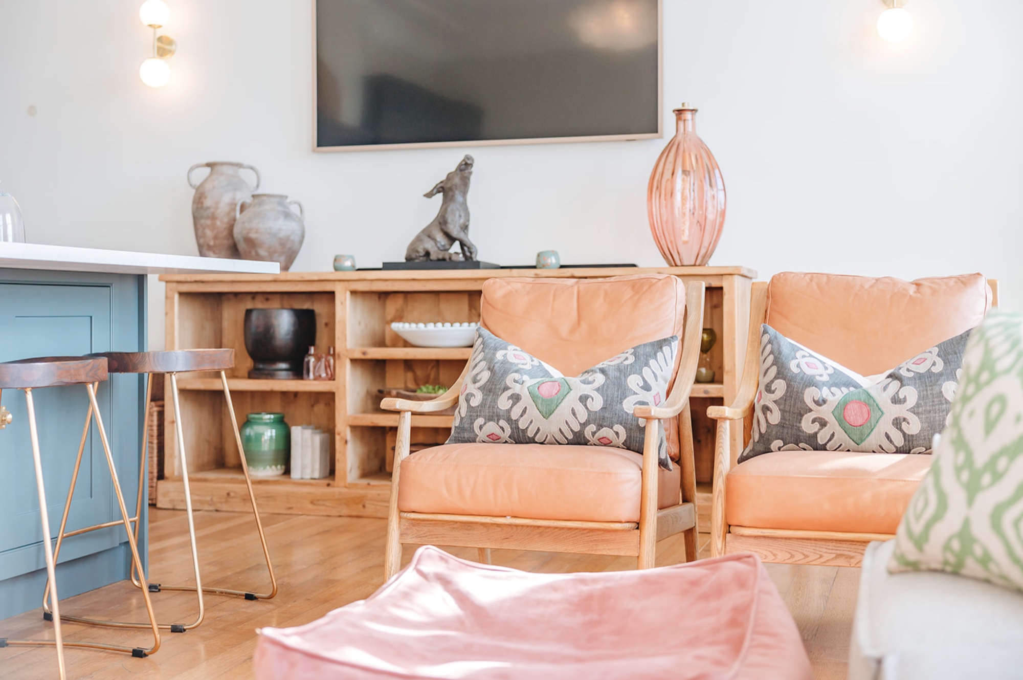 Sitting area within the kitchen with two tan leather armchairs, patterned cushions and a low timber cabinet