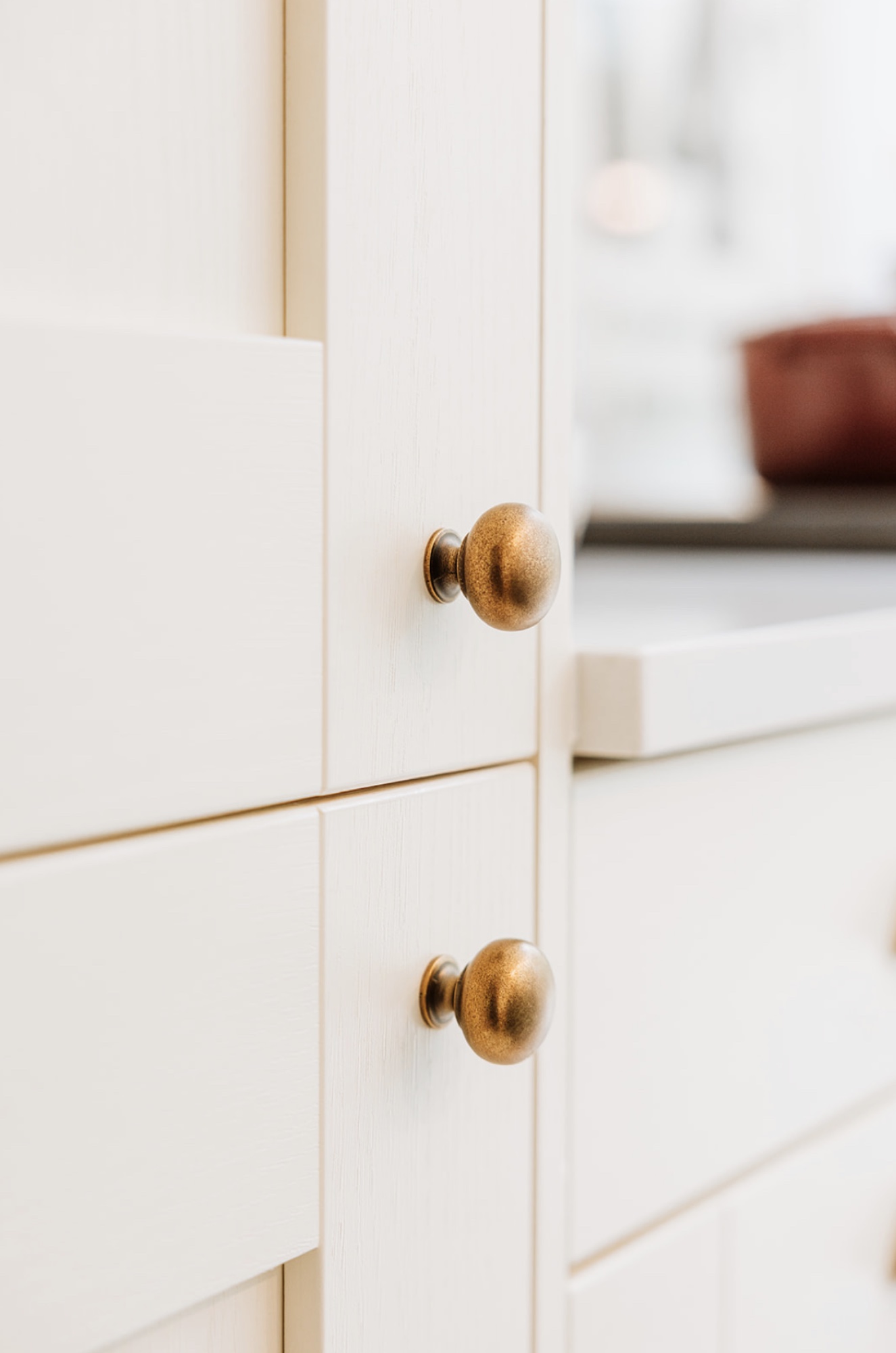 Pair of antique brass knobs on pale shaker-style cabinet doors
