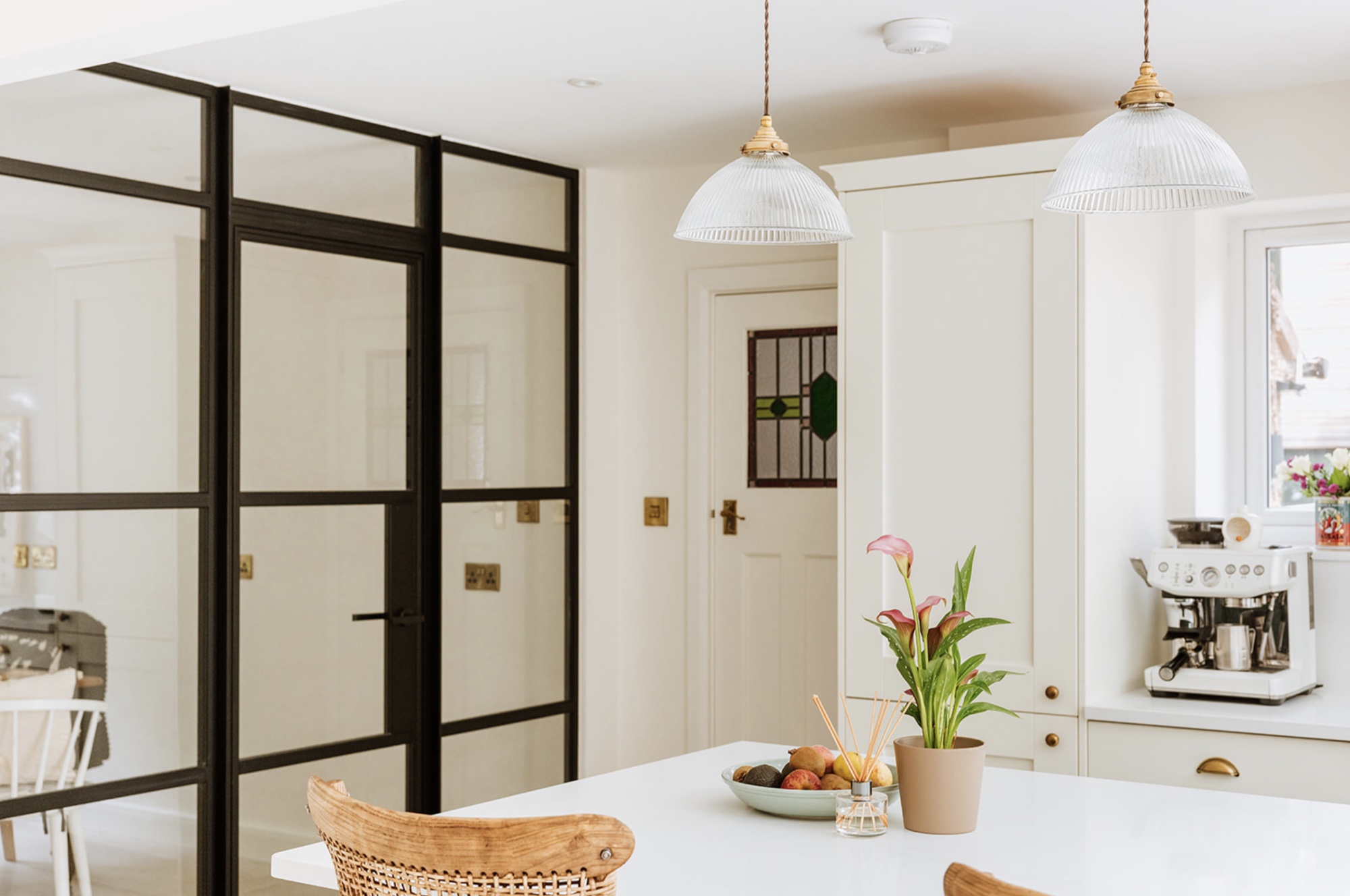 Wide view across the kitchen island towards the black-framed glazed screen