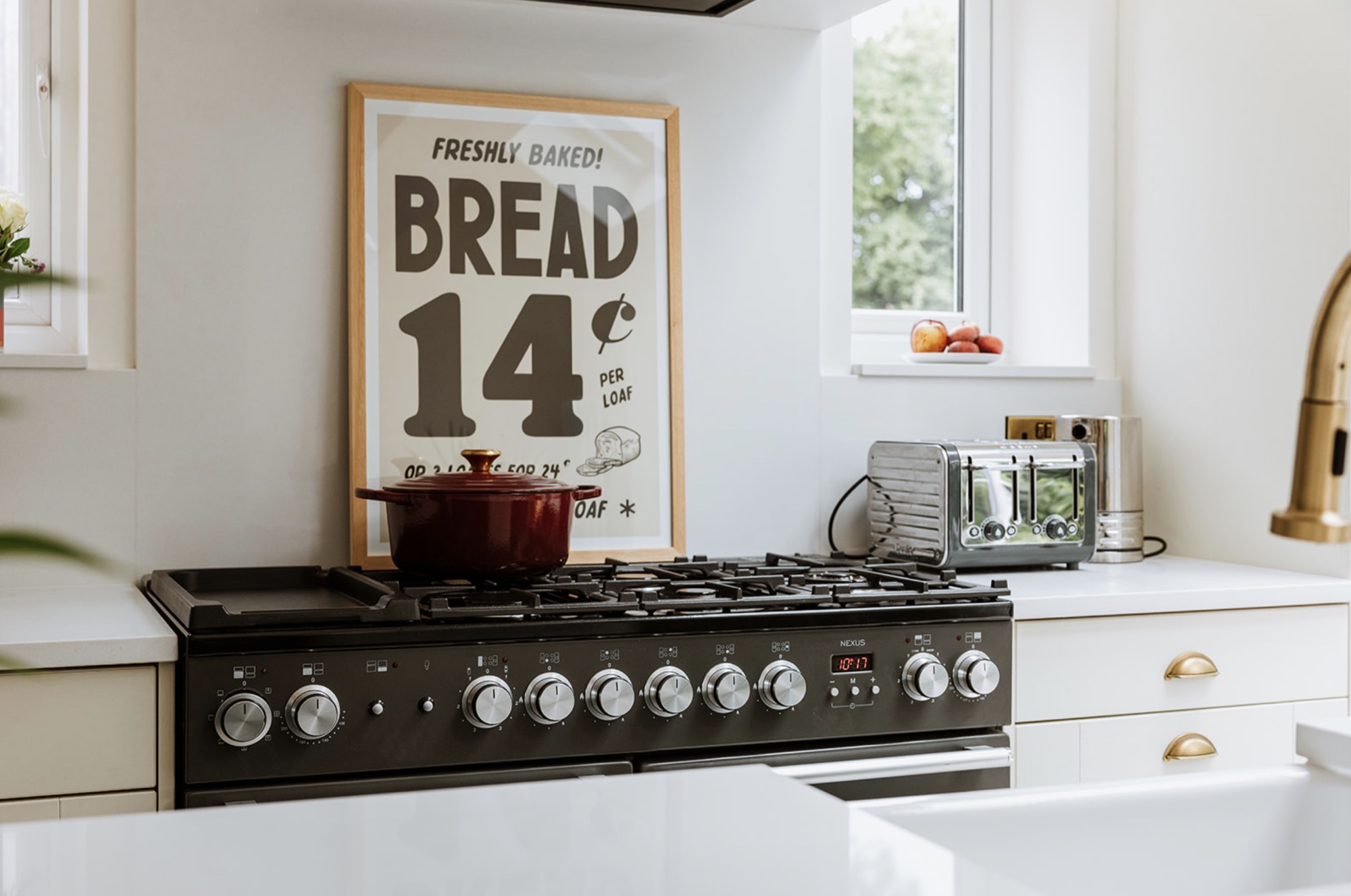 Black range cooker, framed bread print and polished toaster in the pale Fairholm kitchen