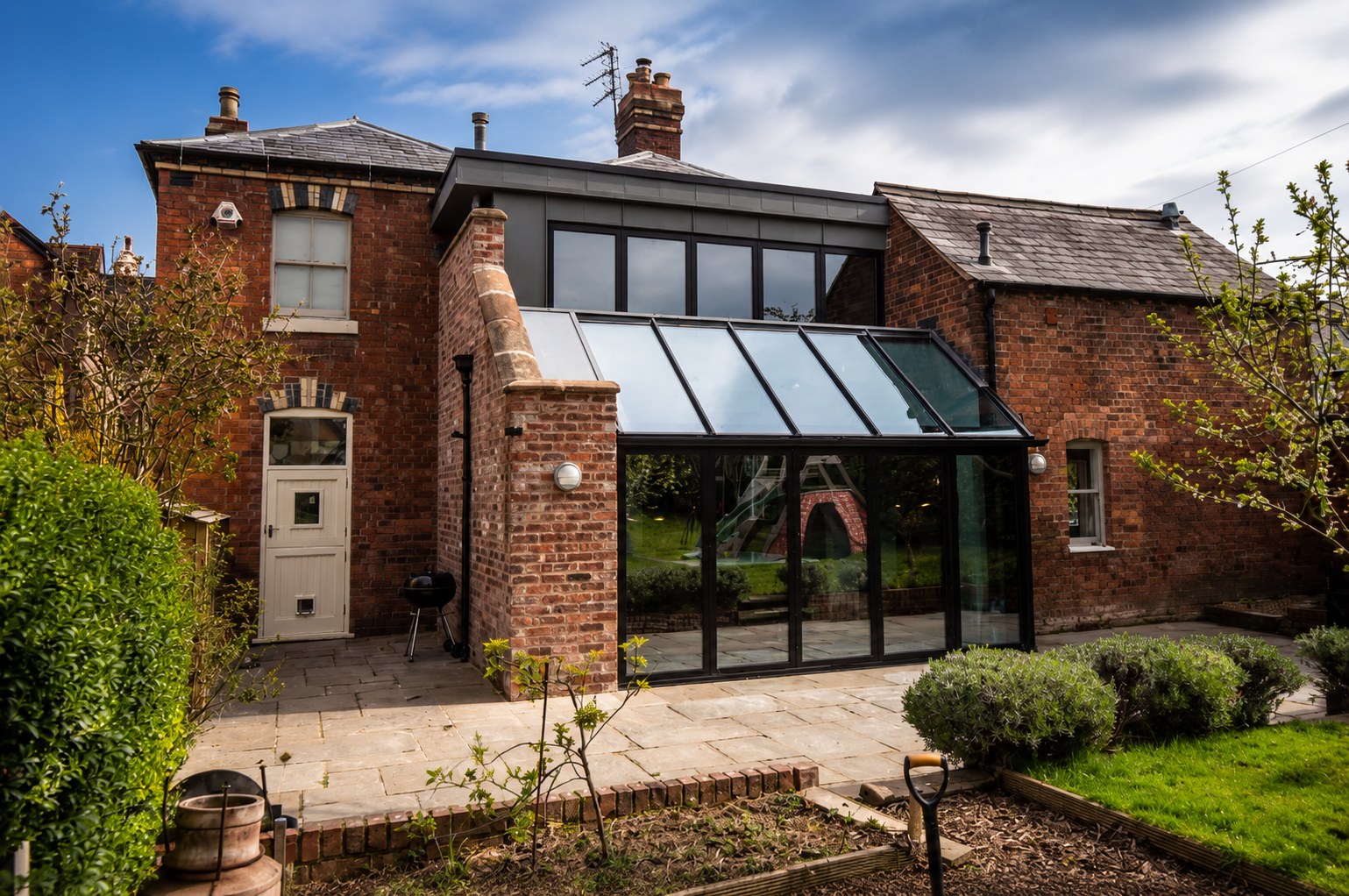 Oakleigh House, Shrewsbury: a Victorian lodge with a glazed lean-to extension and zinc-clad upper storey seen from the garden