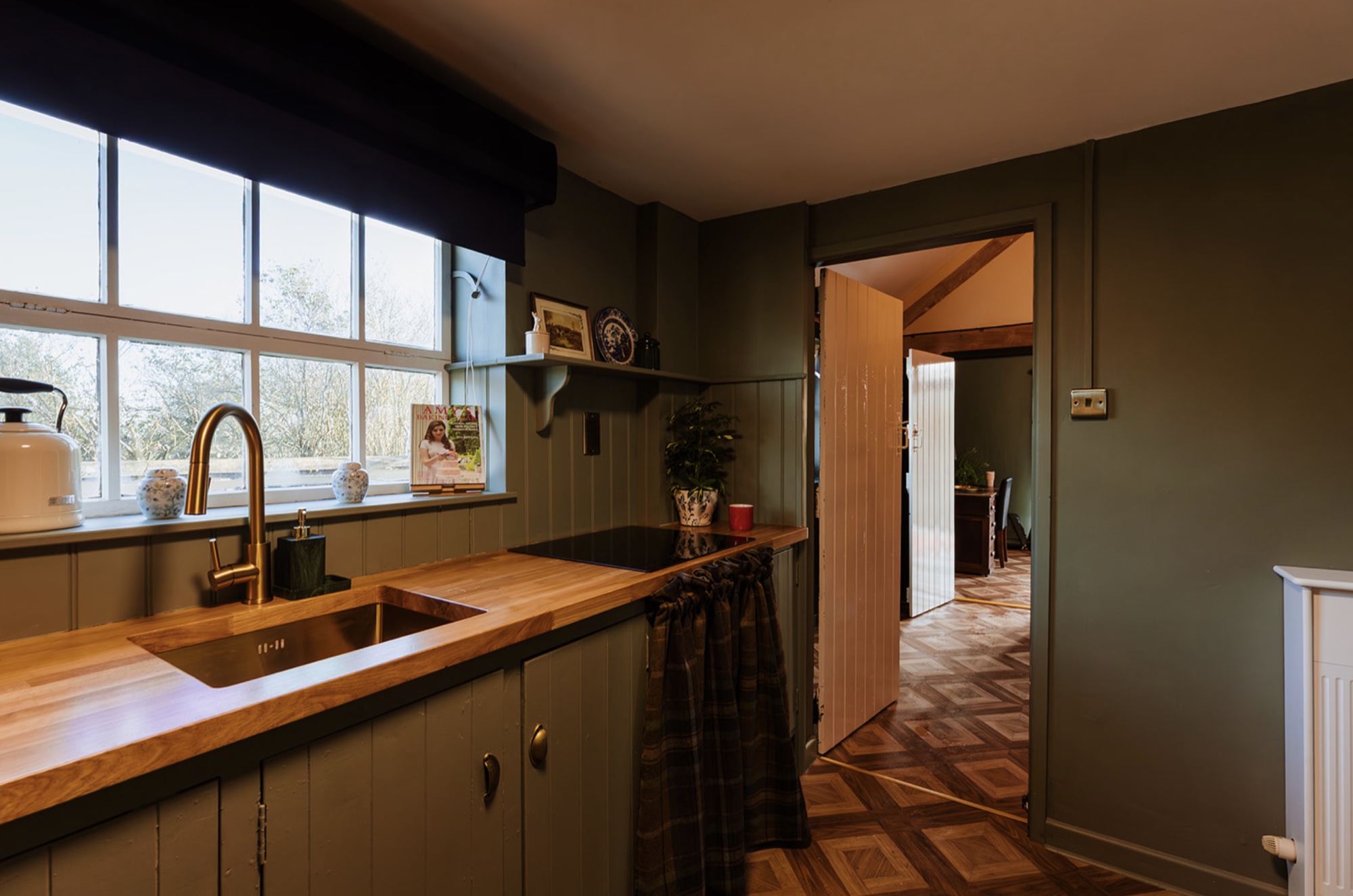 Pool House kitchenette with oak worktop, green cabinetry and a view through to the adjoining room
